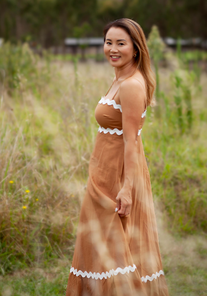 Full body image of Rasamy the celebrant joyous and carefree with her shoes off in an outdoor setting